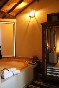 y baño con bañera con luz y espejo. en Chalés das Orquídeas, en Visconde De Maua