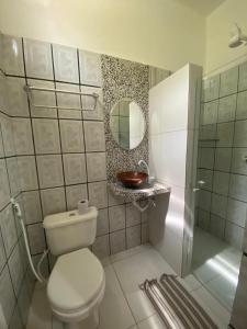 uma casa de banho com um WC, um chuveiro e um espelho. em Pousada Pedra Furada em Jericoacoara