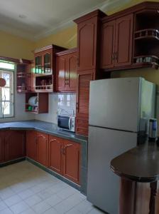 een keuken met houten kasten en een witte koelkast bij Villa Sayang Humairah @ Venice of Perak Intan 2 in Lumut