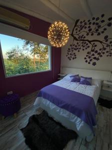 a bedroom with a purple bed and a chandelier at Posada de Sofi in Concordia