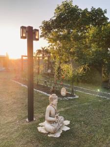 a statue of a woman sitting on the grass next to a pole at La Posada de Sofi in Concordia