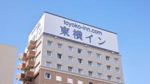 a building with a sign on the top of it at Toyoko Inn Higashi hiroshima Ekimae in Higashihiroshima