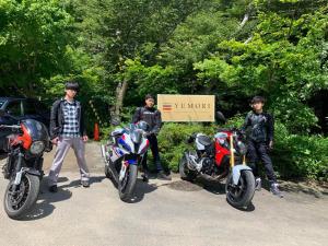 福島市にあるYUMORI ONSEN HOSTELの三人の少年が二輪車の隣に立っている
