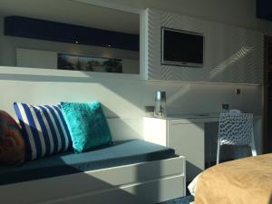 a bedroom with a couch and a tv on a wall at SoBlue Hôtel in Antibes