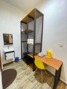 Cette chambre comprend un bureau et une table avec une chaise jaune. dans l'établissement Kedawang Village Langkawi, à Pantai Cenang
