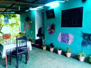 Zimmer mit einem Tisch und einer blauen Wand mit Pflanzen in der Unterkunft Cozy House Hostel in Ella