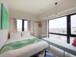 Tabino Hotel lit Miyakojima في جزيرة مياكو: غرفة فندقية بسريرين ونافذة كبيرة