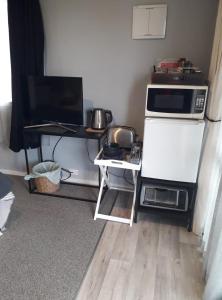 a kitchen with a refrigerator and a table with a microwave at Rural Gordonton Sleepout in Hamilton