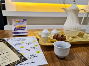 una mesa con un plato de comida y una taza de leche en Shams Alshate شمس الشاطئ, en Buraidah
