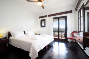 カラタスにあるCasa Bella Vistaの白いベッドルーム(ベッド1台、大きな窓付)