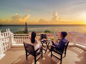 SV Boutique Resort في فنغ تاو: رجل وامرأة يجلسان على شرفة تطل على المحيط