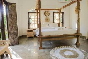 a bedroom with a canopy bed and a rug at Bramasa Ubud Guest House in Ubud