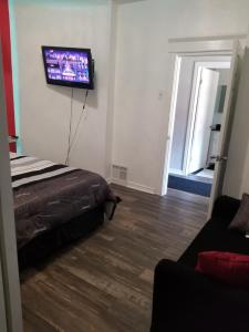 漢密爾頓的住宿－Cozy and unique getaway，卧室配有一张床和壁挂式平面电视。