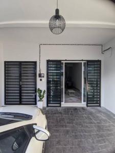 a bedroom with black shutters and a car in a room at Cikgu I&S Homestay in Jitra