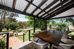 an outdoor patio with a wooden table and chairs at Historic Riverfront Residence Farmstay in Cullenbone