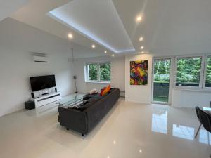 a living room with a couch and a tv at White House Izabelin Family SPA House near Warsaw in Mogielnica