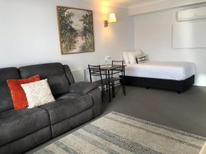 a living room with a couch and a bed at Avaleen Lodge Motor Inn in Nowra