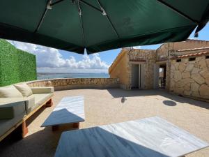 een patio met een bank en een parasol bij Villa vue sur mer in El Djamila