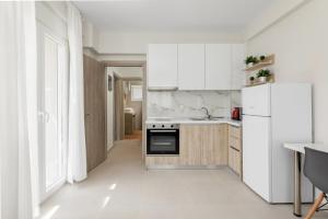 a kitchen with white cabinets and a white refrigerator at V Luxury Apartments with Pool in Siviri