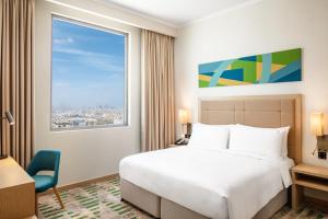 une chambre d'hôtel avec un lit et une fenêtre dans l'établissement Holiday Inn & Suites - Dubai Science Park, an IHG Hotel, à Dubaï