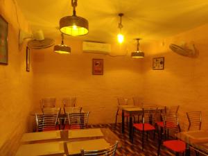 a dining room with tables and chairs and lights at Heritage Bagala Dharmasala in Puri