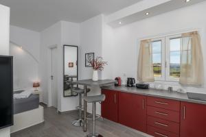 a kitchen with red cabinets and a table and a window at Sunset Village 4 in Paleochori