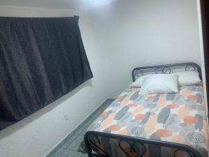 Dormitorio pequeño con cama con edredón en Alojamiento Morelos, en Ciudad de México