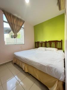 ein Schlafzimmer mit einem großen Bett und einer grünen Wand in der Unterkunft Joyful Motel in Kuah