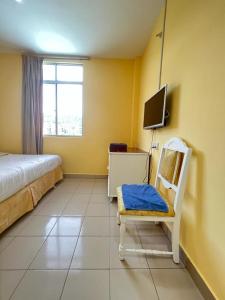 ein Schlafzimmer mit einem Bett, einem Stuhl und einem TV in der Unterkunft Joyful Motel in Kuah
