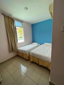 2 Betten in einem Zimmer mit blauer Wand in der Unterkunft Joyful Motel in Kuah