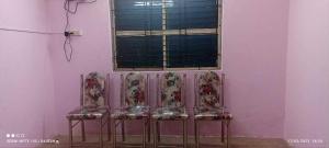 drie stoelen voor een roze muur met een raam bij OYO Aaradhya Hotel &restaurant in Parādīp Garh