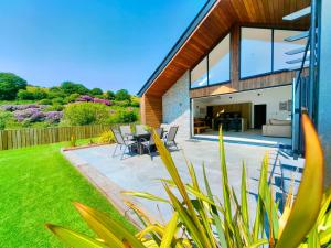 a house extension with a patio and a garden at New build Luxurious PALMA VILLA IN CORNWALL! 4miles EDEN PROJECT, 4 miles Beach & Harbour! Open plan, One level Living area Ground floor, Private location, Encllosed Garden, Underfloor Heating, Coffee Machine,near WALKING-CYCLING PATH in St Austell