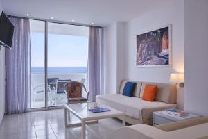 uma sala de estar com um sofá e uma mesa em Epsilon Hotel Apartments em Faliraki