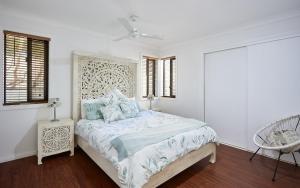 a white bedroom with a bed and a chair at Large, Light, dog friendly home 600m to Burleigh beach in Gold Coast