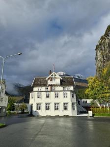 a large white building with mountains in the background at Sylte Hotell, Valldal in Valldal +49 photos