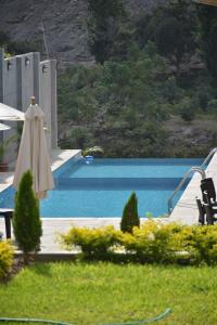 a pool with an umbrella and a table and chairs and a swimming pool at Jalara Lunahuaná Hotel in Lunahuaná