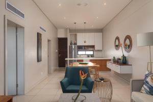 a living room with a blue chair and a kitchen at Indigo 2 Bed Zimbali Suites Sea View in Ballito +11 photos