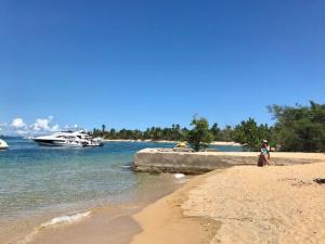 a woman walking on a beach with a boat in the water at Retiro de la Pasión Segundo in Destino