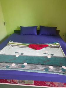 ein Bett mit violetter Bettwäsche und einer roten und weißen Decke in der Unterkunft Nadil Homestay in Kuta Lombok
