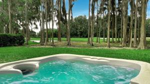 una piscina en medio de un campo con árboles en 5 Room TampaGolfVillas by AmericanVacationliving, en Wesley Chapel