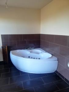 a white tub in a bathroom with brown tiles at Peace & Quiet in Sławoborze