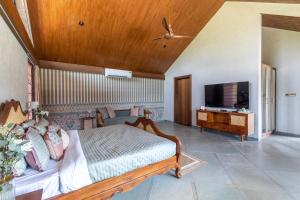 a bedroom with a bed and a flat screen tv at StayVista's The Barn - Mountain-View Luxury Mansion with Heated Infinity Pool, Deck, Jacuzzi, Lawn featuring a Gazebo and Firepit in Lonavala