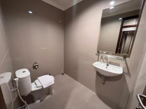 ein Badezimmer mit einem Waschbecken, einem WC und einem Spiegel in der Unterkunft LE SEMAR HOTEL KARAWACI in Dahung