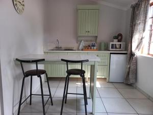 a kitchen with two bar stools and a white counter at Lemon Tree Manor- Country Cottage in Groblersdal