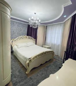 a bedroom with a large bed and a chandelier at Ak-Orgo guest house in Bishkek