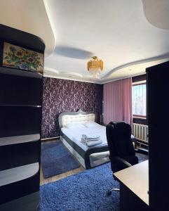 a bedroom with a bed and a desk and a chair at Ak-Orgo guest house in Bishkek
