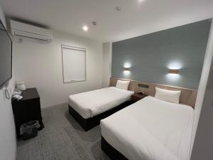 a hotel room with two beds and a window at PLAZA IN KANKU Hotel in Sano