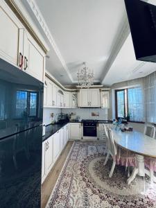 a kitchen with white cabinets and a table with chairs at Ak-Orgo guest house in Bishkek