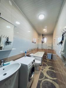 ein Badezimmer mit einer Waschmaschine und einem Waschbecken in der Unterkunft Ak-Orgo guest house in Bischkek