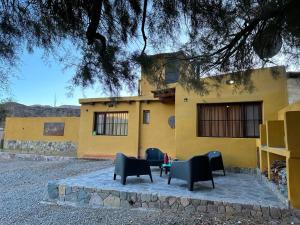 a yellow building with chairs in front of it at Cabañas Inti Raymi in Huacalera